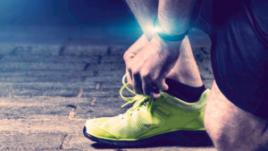 Kondiløber snører sine løbesko, fokus på wearables/smart device på armen