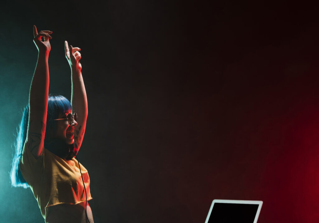 dj with hands raised mixing console